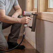 Carpenter using the meite USA F32 18 gauge pneumatic brad nailer to install wood trim around an interior window